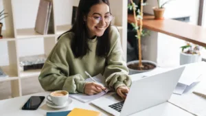 Chica sonriente utilizando un portátil, disfrutando de una experiencia positiva mientras trabaja o estudia en su computadora.